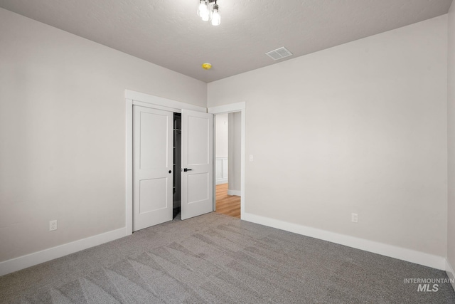 unfurnished bedroom with baseboards, visible vents, carpet floors, and a textured ceiling