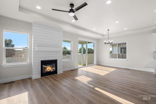 unfurnished living room with a wealth of natural light, visible vents, a raised ceiling, and wood finished floors