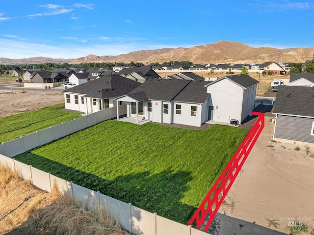 view of front of house with a mountain view, a residential view, a fenced backyard, and a front yard