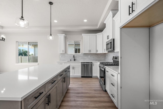 kitchen featuring light wood-style flooring, a sink, backsplash, appliances with stainless steel finishes, and white cabinets