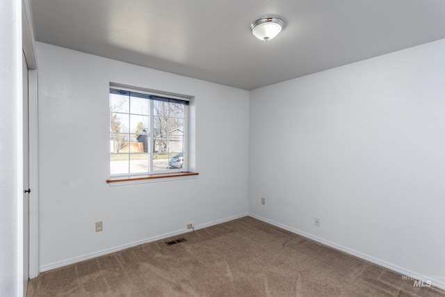 carpeted spare room featuring baseboards and visible vents