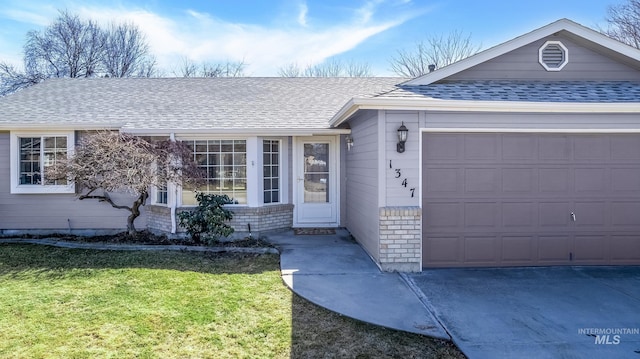 ranch-style house with roof with shingles, an attached garage, a front lawn, concrete driveway, and brick siding