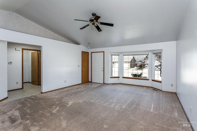 interior space with vaulted ceiling, carpet flooring, a ceiling fan, and baseboards