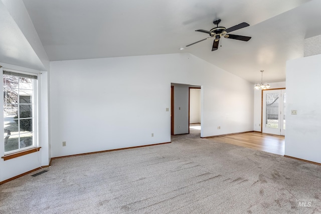 carpeted spare room featuring visible vents, ceiling fan with notable chandelier, baseboards, and lofted ceiling