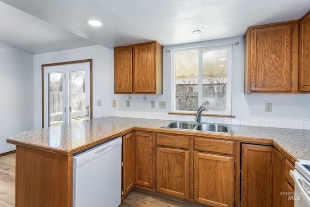 kitchen featuring dishwasher, brown cabinets, a peninsula, stove, and a sink