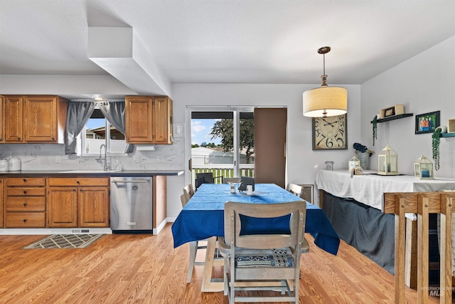 3404 Chukar Ln, Clarkston, WA 99403 - kitchen featuring dishwasher, brown cabinets, light wood-style flooring, backsplash, and hanging light fixtures