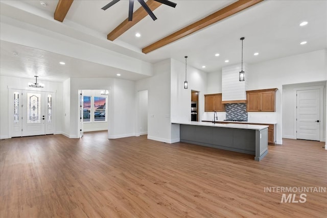 kitchen featuring decorative backsplash, ceiling fan, decorative light fixtures, hardwood / wood-style flooring, and beamed ceiling