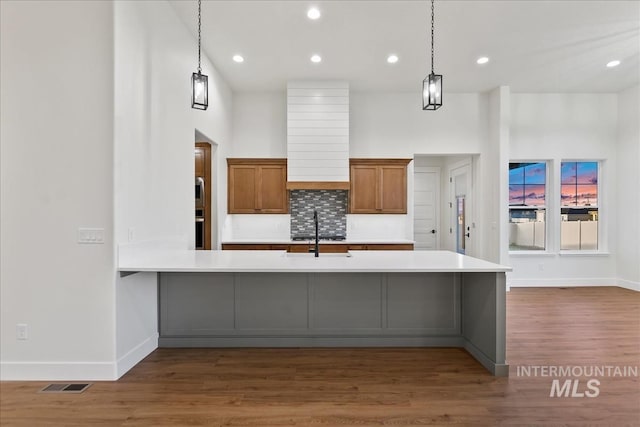 kitchen featuring pendant lighting, sink, decorative backsplash, a towering ceiling, and dark hardwood / wood-style flooring