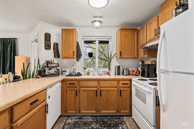 kitchen featuring under cabinet range hood, light countertops, white appliances, and a sink