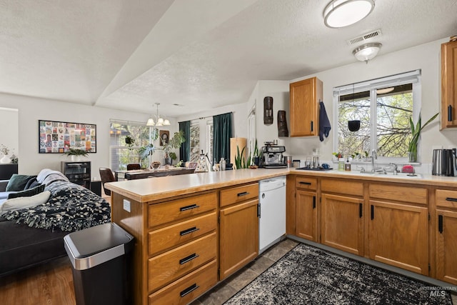 kitchen featuring visible vents, white dishwasher, a peninsula, open floor plan, and a notable chandelier