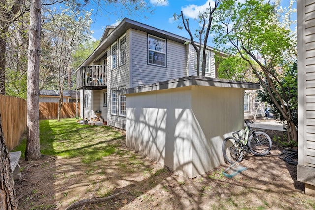 view of property exterior with a lawn, fence, and a balcony