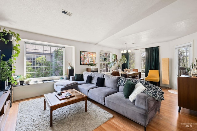 living room featuring plenty of natural light, a textured ceiling, light wood finished floors, and visible vents