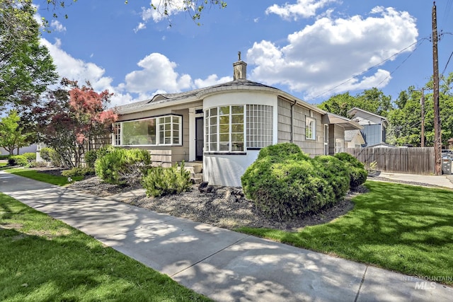 view of side of property featuring a yard, fence, and a chimney