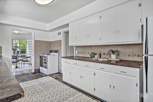 kitchen featuring dark countertops, electric range, freestanding refrigerator, and visible vents