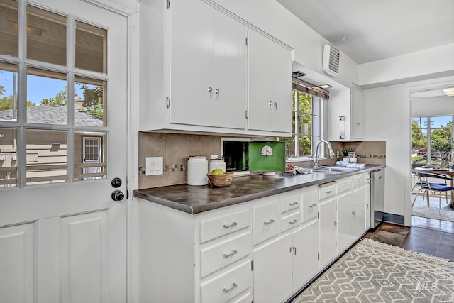 kitchen featuring backsplash, dishwasher, plenty of natural light, white cabinets, and a sink