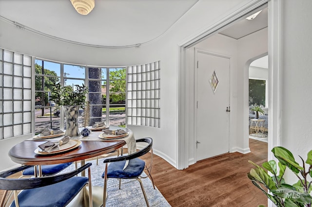 dining area featuring baseboards, arched walkways, and wood finished floors