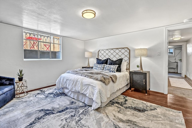 bedroom with a textured ceiling, baseboards, and wood finished floors