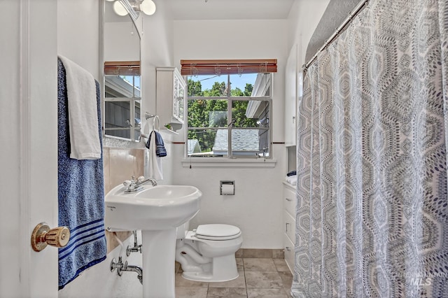 bathroom featuring a shower with shower curtain, toilet, and tile patterned flooring