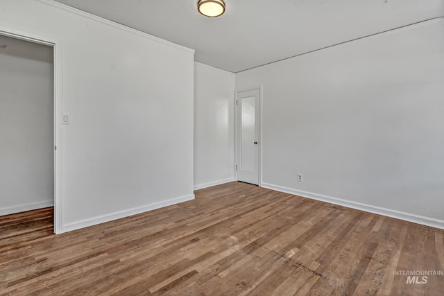 spare room with baseboards and wood finished floors