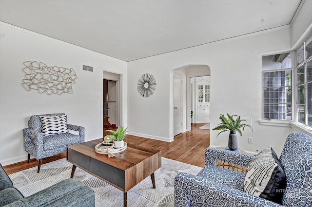 living room with visible vents, arched walkways, baseboards, and wood finished floors