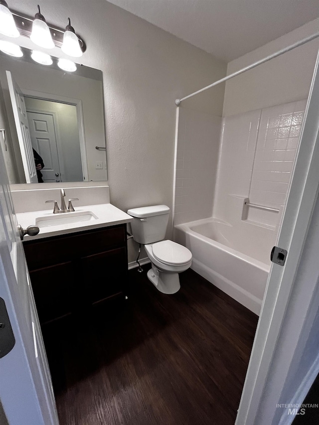 full bathroom with a textured wall, toilet, vanity, shower / tub combination, and wood finished floors