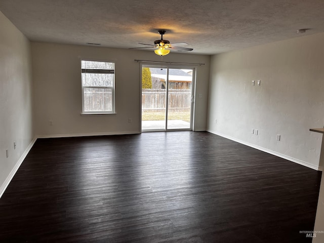 empty room featuring ceiling fan, a textured ceiling, baseboards, and dark wood-type flooring