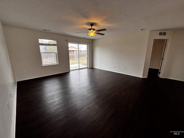 spare room featuring dark wood-type flooring, visible vents, ceiling fan, and a textured ceiling