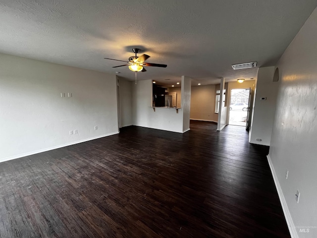 unfurnished living room with a textured ceiling, visible vents, dark wood finished floors, and a ceiling fan