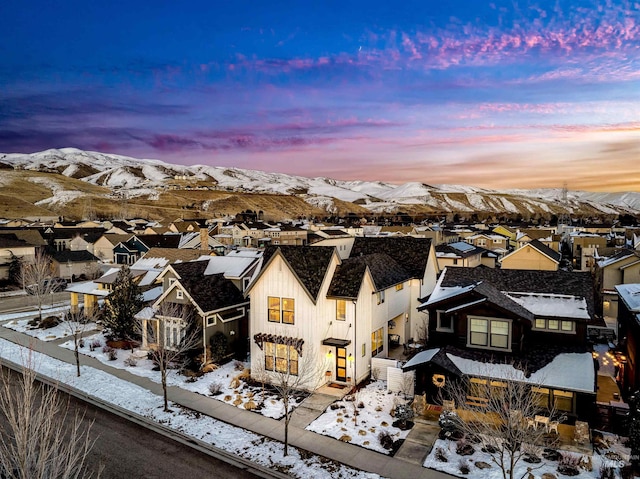 snowy aerial view featuring a residential view and a mountain view