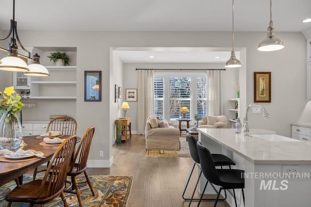 dining room featuring built in shelves, recessed lighting, wood finished floors, and baseboards