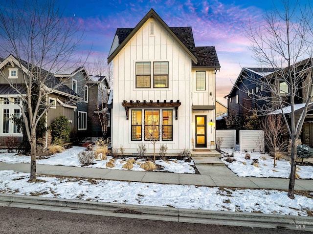 modern farmhouse featuring board and batten siding, roof with shingles, and fence