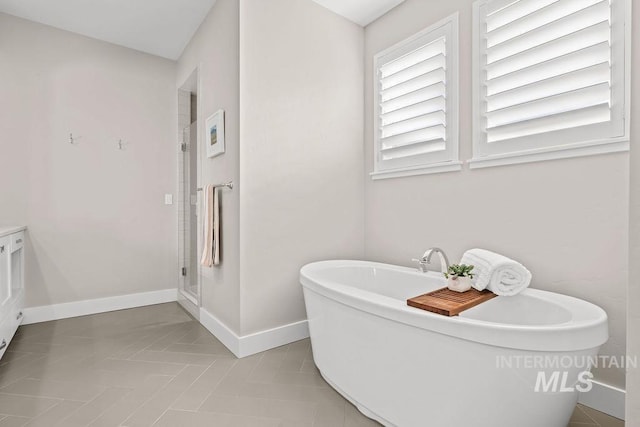 full bath with a freestanding tub, baseboards, and a stall shower