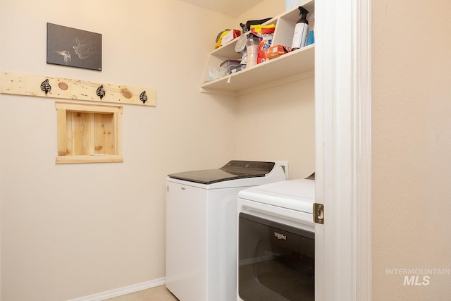 clothes washing area with washing machine and dryer, laundry area, and baseboards