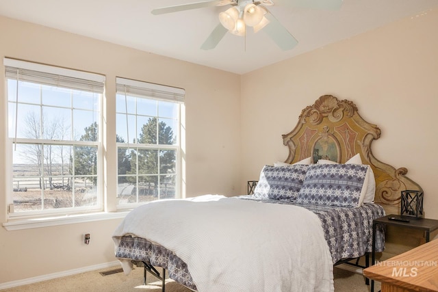 carpeted bedroom featuring a ceiling fan, visible vents, and baseboards