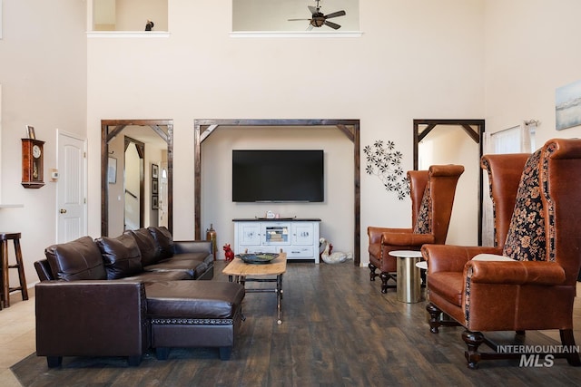 living room featuring a towering ceiling, ceiling fan, and wood finished floors