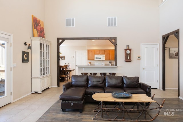 living room with baseboards, a high ceiling, visible vents, and arched walkways