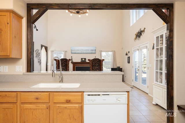 kitchen featuring light countertops, white dishwasher, a sink, and light tile patterned flooring