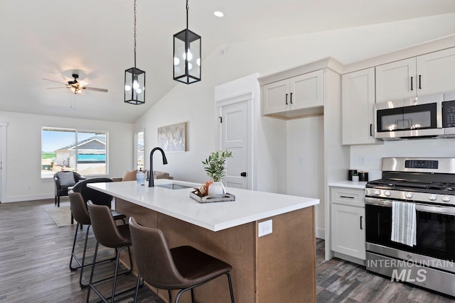 kitchen featuring lofted ceiling, stainless steel appliances, dark wood-style flooring, a sink, and hanging light fixtures