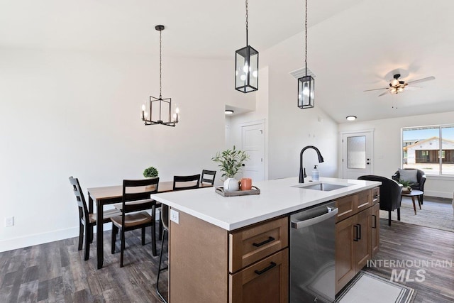 kitchen featuring dark wood-style flooring, a center island with sink, hanging light fixtures, stainless steel dishwasher, and a sink