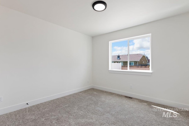 carpeted spare room with visible vents and baseboards