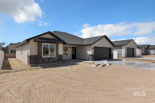 view of front of home with a garage, stone siding, fence, and driveway