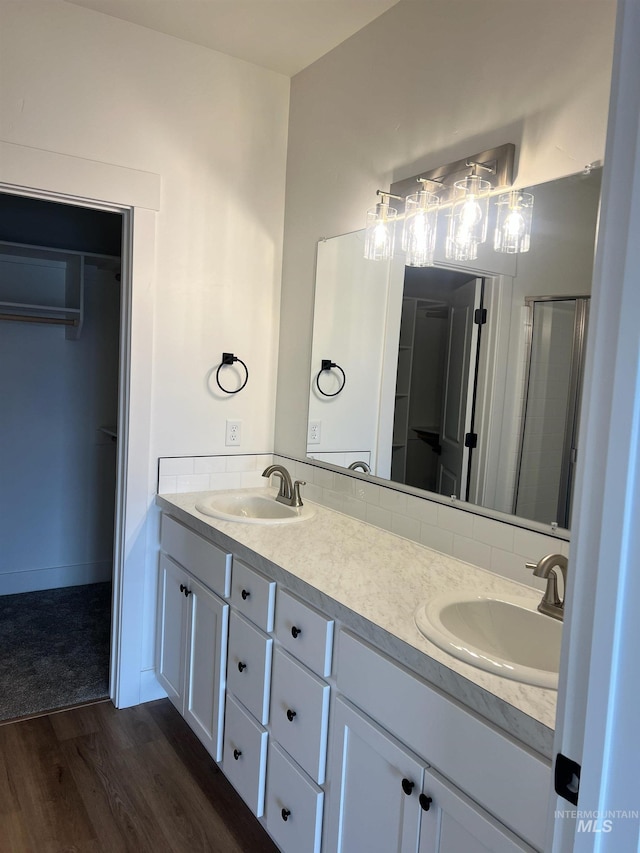 bathroom with tasteful backsplash, vanity, hardwood / wood-style flooring, and a shower with shower door