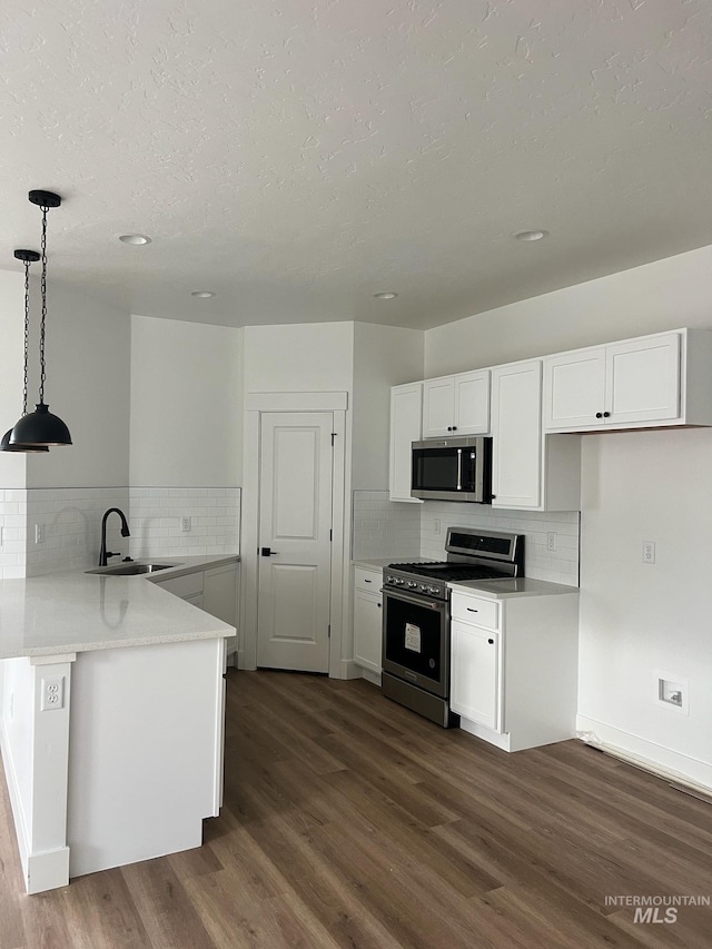 kitchen featuring sink, hanging light fixtures, stainless steel appliances, white cabinets, and kitchen peninsula