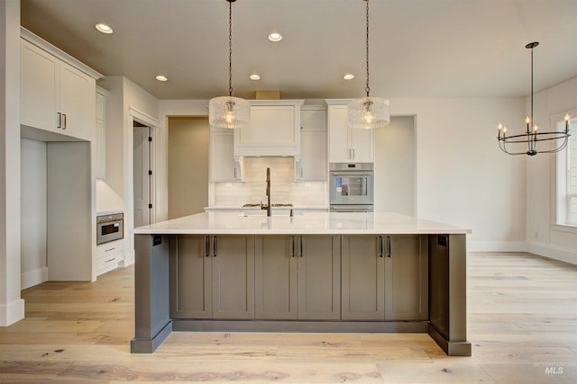 1149 E Crescendo St, Meridian, ID 83642 - kitchen with oven, a chandelier, decorative backsplash, a large island with sink, and light wood-style flooring