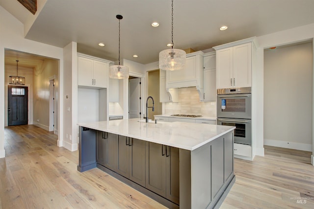 1149 E Crescendo St, Meridian, ID 83642 - kitchen with double oven, gas cooktop, white cabinetry, a large island with sink, and tasteful backsplash