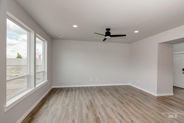 unfurnished room with a wealth of natural light, ceiling fan, and light hardwood / wood-style floors