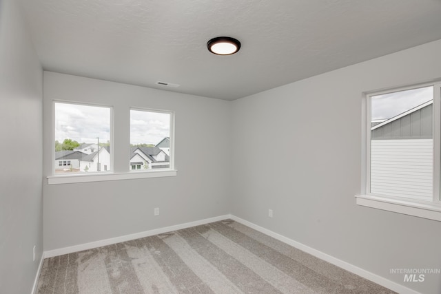 carpeted empty room featuring a textured ceiling