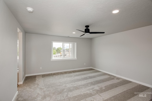 carpeted spare room with ceiling fan and a textured ceiling