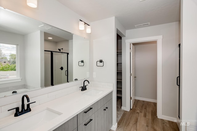 bathroom with hardwood / wood-style flooring, vanity, backsplash, and walk in shower