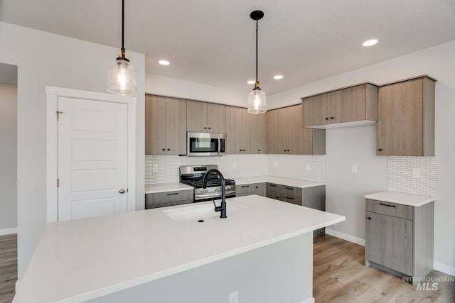 kitchen featuring backsplash, pendant lighting, light brown cabinetry, appliances with stainless steel finishes, and light wood-type flooring